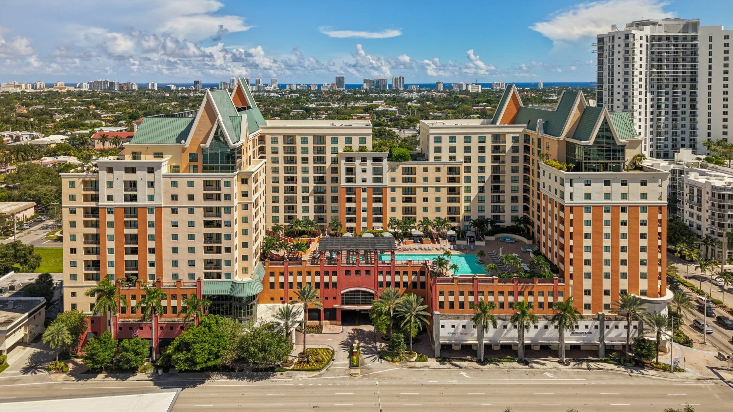 Front aerial of The Waverly at Las Olas with the pool deck and the ocean on the horizon
